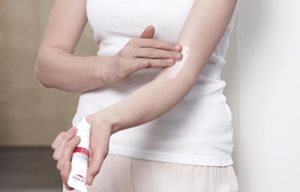 Ženska nanaša Eucerin AtopiControl acute negovalno kremo na komolec.