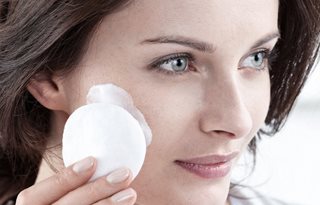 Ženska nanaša čistilno mleko na blazinico vate.